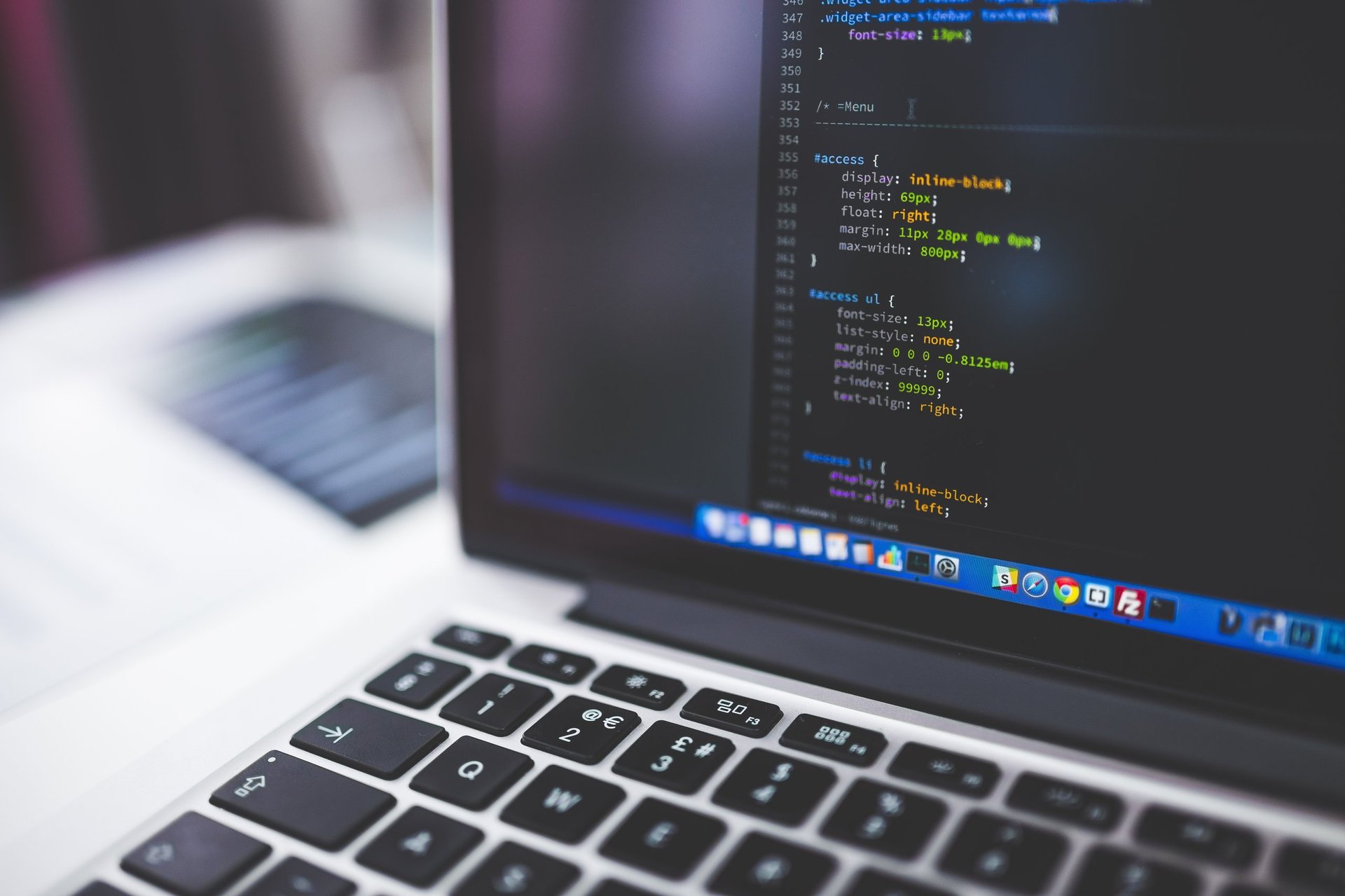 Laptop displaying code editor with colored syntax highlighting and programming text visible on screen